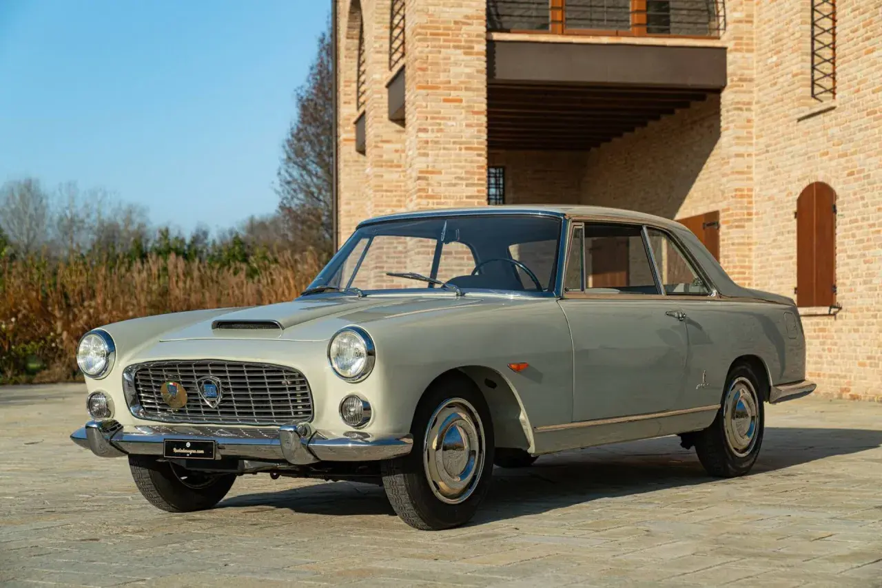 Eine elegante Lancia Flaminia Coupé steht vor einem Backsteinhaus.
