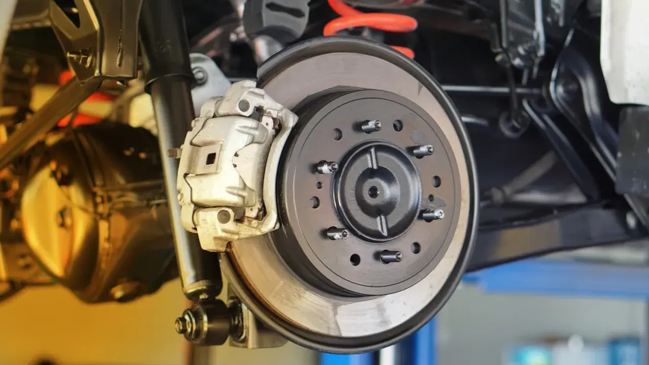 Nahaufnahme einer Autobremsanlage. Ein Mechaniker prüft, wann bremsscheiben wechseln, um die Sicherheit zu gewährleisten.