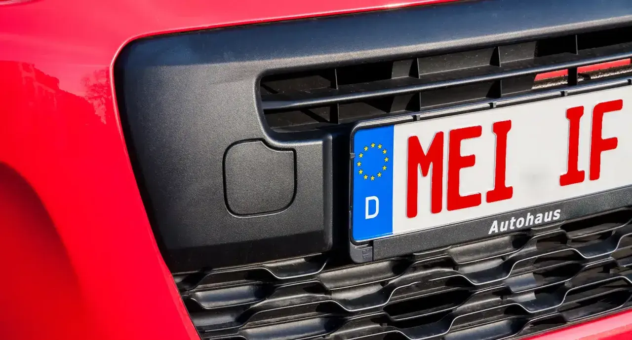 Rotes Kennzeichen "MEI IF" an einem roten Auto, bereit für das Fahrtenbuch.
