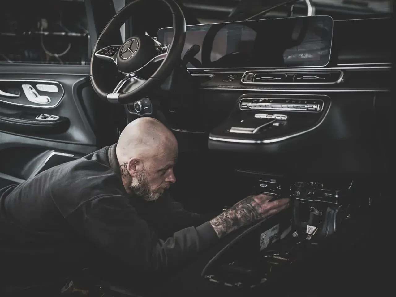 Ein Mechaniker mit Tattoos repariert den Anlasser eines modernen Autos.