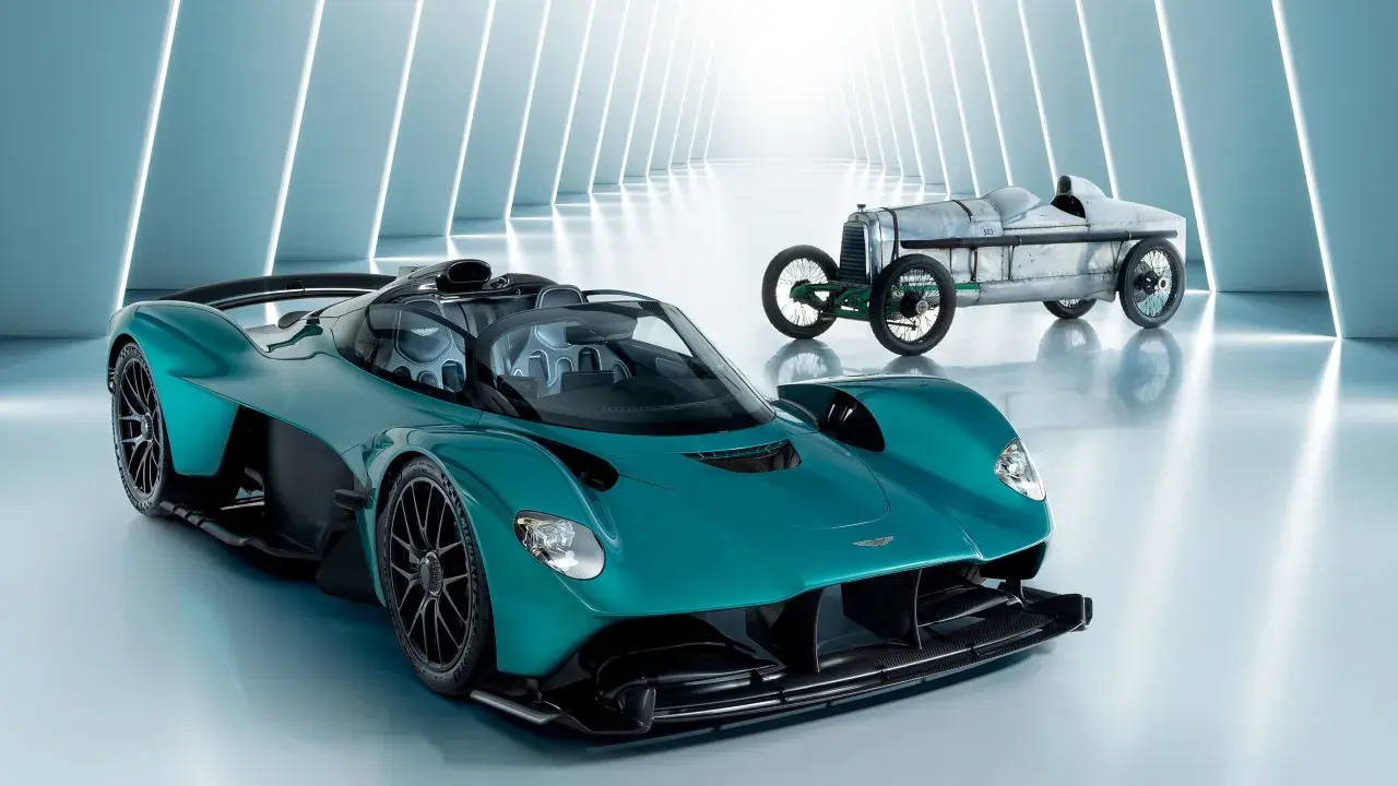 Ein moderner Aston Martin Valkyrie neben einem historischen Rennwagen.