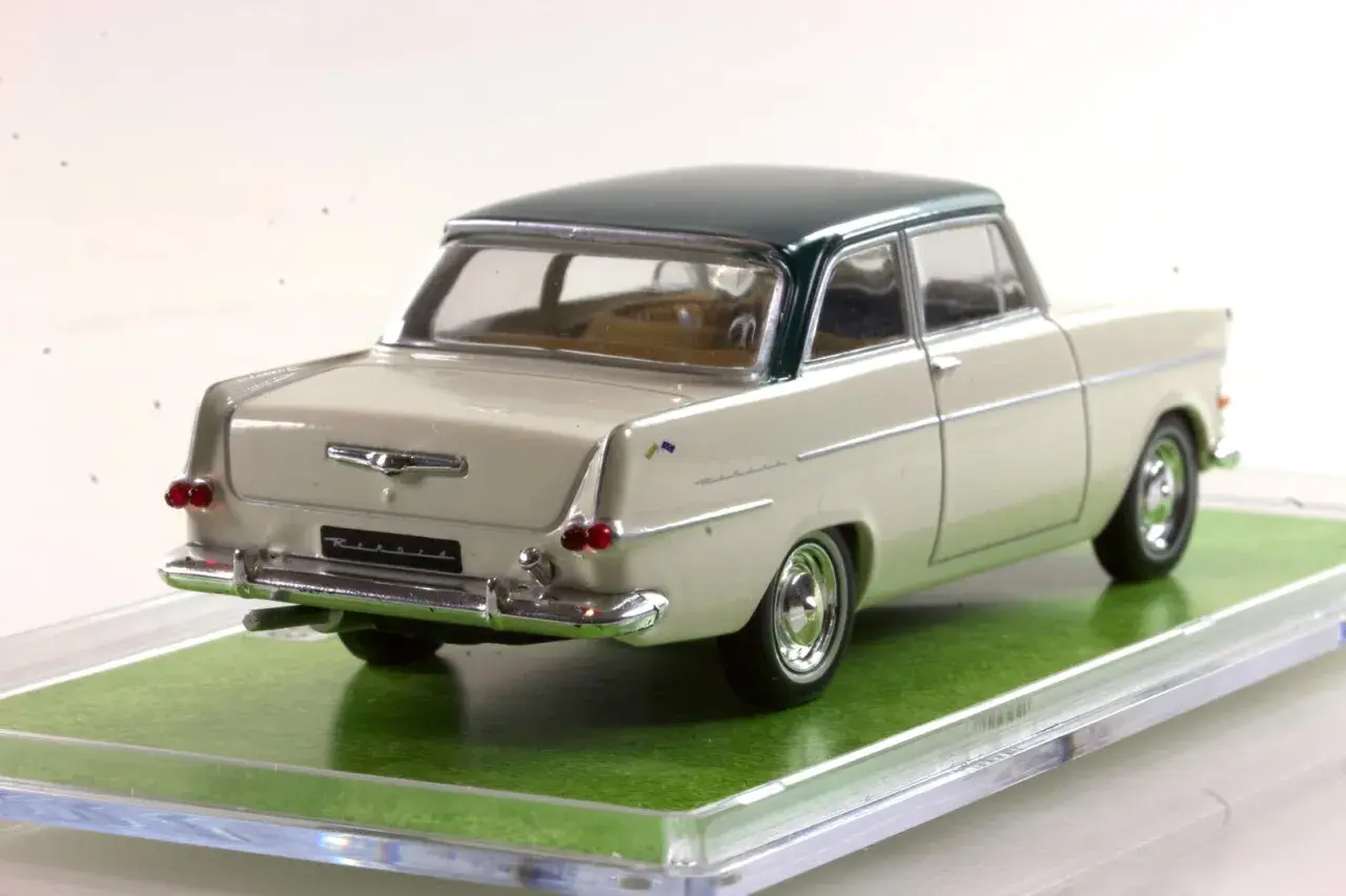 Ein cremefarbener Opel Rekord 1960 als Modellauto mit dunkelgrünem Dach, auf einer grünen Unterlage.
