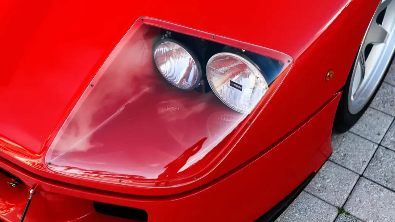 Der rote Ferrari f40 lm mit seinen charakteristischen Scheinwerfern unter einer transparenten Abdeckung.