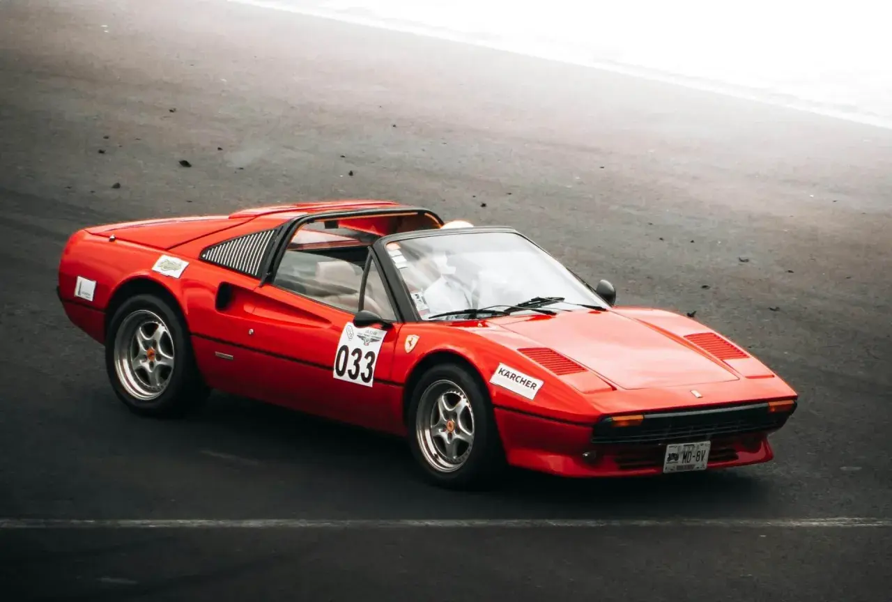 Roter Ferrari 308 GTB mit Startnummer 033 auf der Rennstrecke, bereit für die nächste Runde.