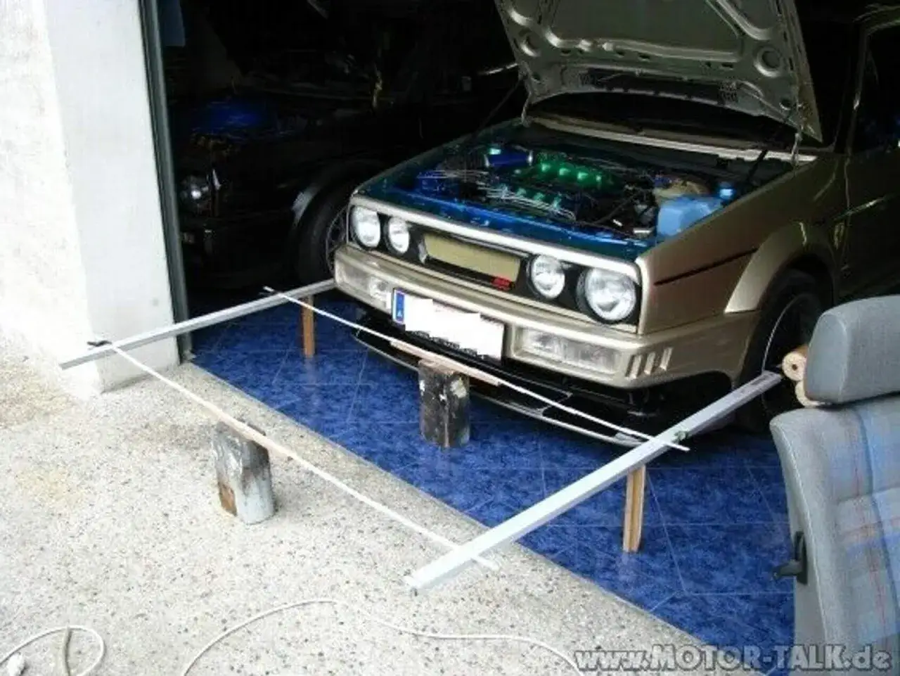 Selbstgemachte Achsvermessung: Ein Golf mit geöffneter Haube und selbstgebautem Messgestell vor dem Auto.
