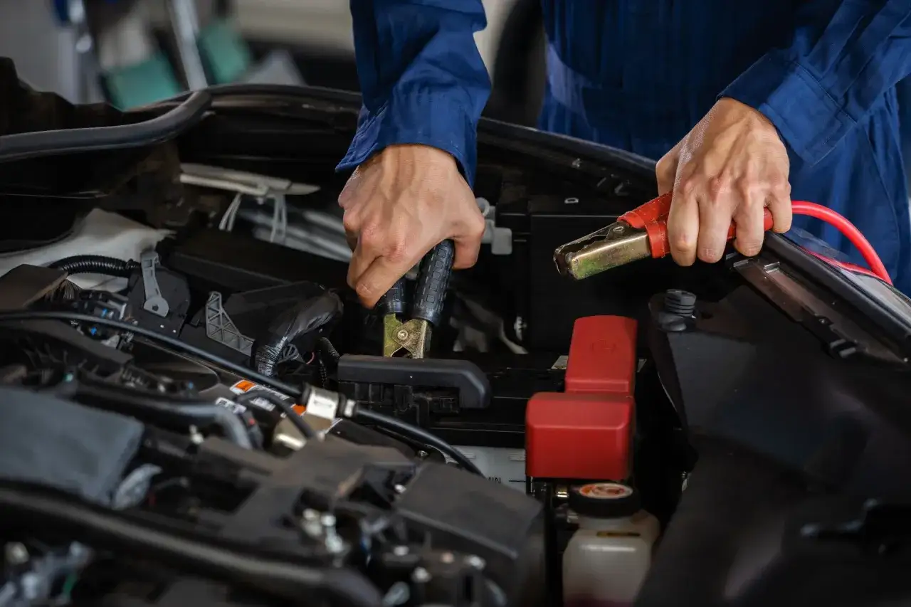 Hände befestigen Klemmen an der Autobatterie, um sie zu laden.