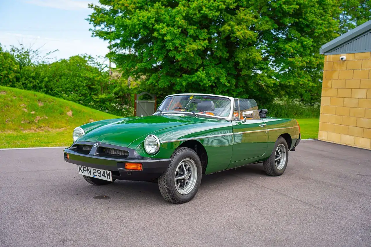 Gr&uuml;ner MG Roadster, ein Klassiker der englischen Automarken der 1960er Jahre, parkt vor einer Scheune.