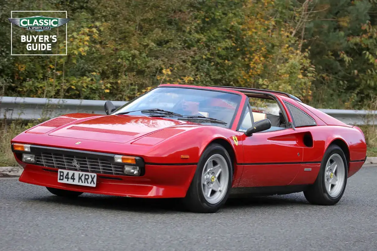 Roter Ferrari 308 GTB Cabriolet f&auml;hrt auf einer Stra&szlig;e, umgeben von B&auml;umen.