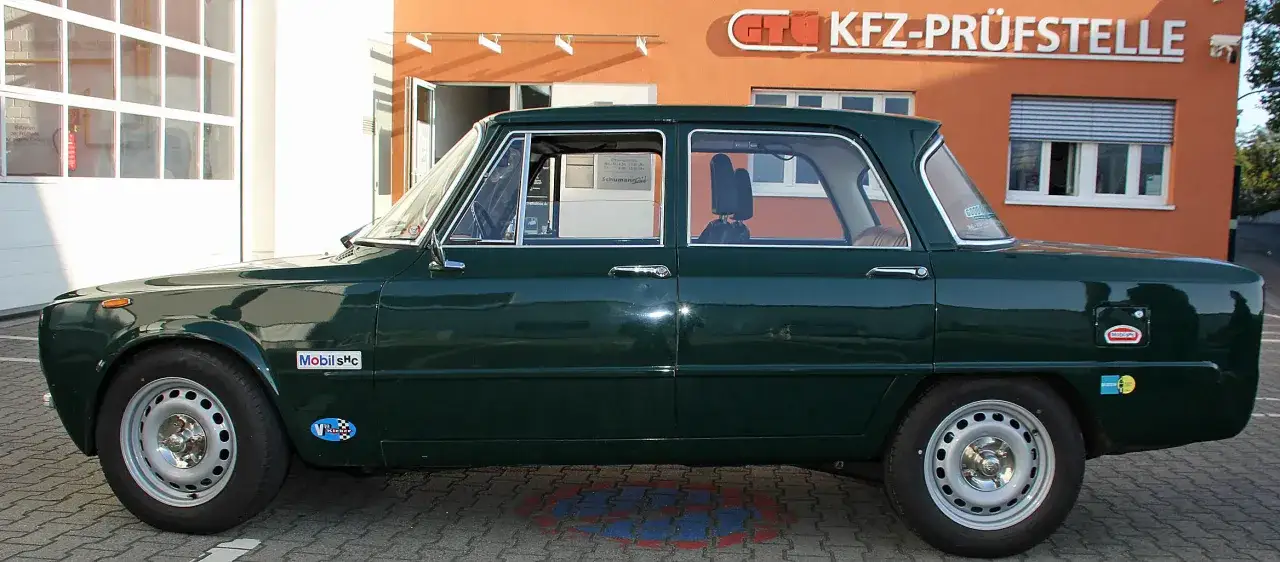 Dunkelgr&uuml;ner Oldtimer vor GT&Uuml; KFZ-Pr&uuml;fstelle. H-Kennzeichen und Aufkleber deuten auf eine km-Begrenzung f&uuml;r Liebhaberfahrzeuge hin.