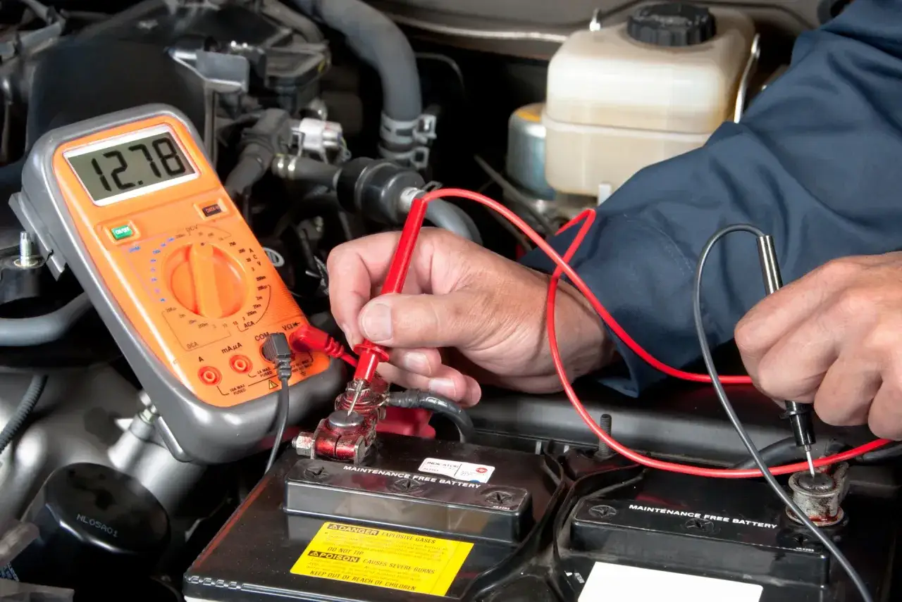 Mechaniker pr&uuml;ft mit Multimeter die Batterie. M&ouml;glicher Defekt am Anlasser bei Mercedes? Kosten f&uuml;r Reparatur pr&uuml;fen.