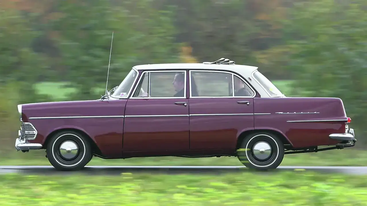 Ein dunkelroter Opel Rekord 1960 f&auml;hrt auf einer Landstra&szlig;e.