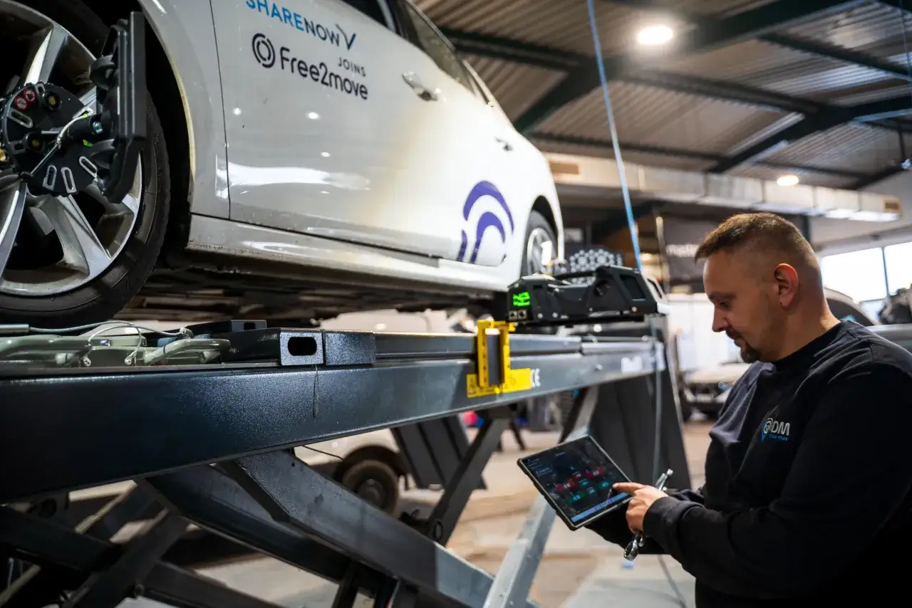 Mechaniker pr&uuml;ft am Tablet die Achsvermessung. Trotz Einstellung zieht das Auto nach rechts.
