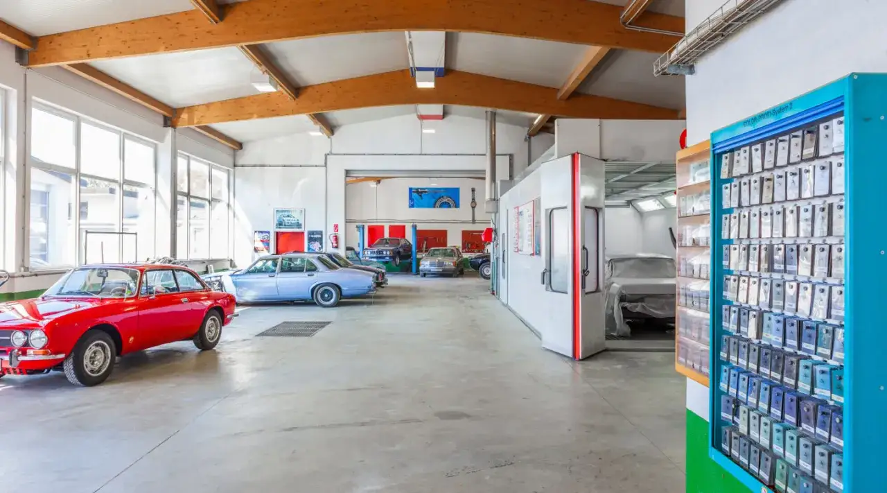 Werkstatt mit Oldtimern, bereit f&uuml;r die Oldtimer Lackierung. Ein roter Alfa Romeo und weitere Klassiker warten auf frische Farbe.