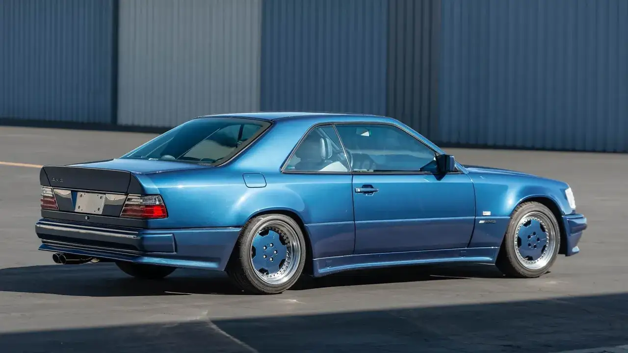 Blauer Mercedes Hammer Coupe mit breiten Kotflügeln und markanten Felgen steht vor einer blauen Wand.