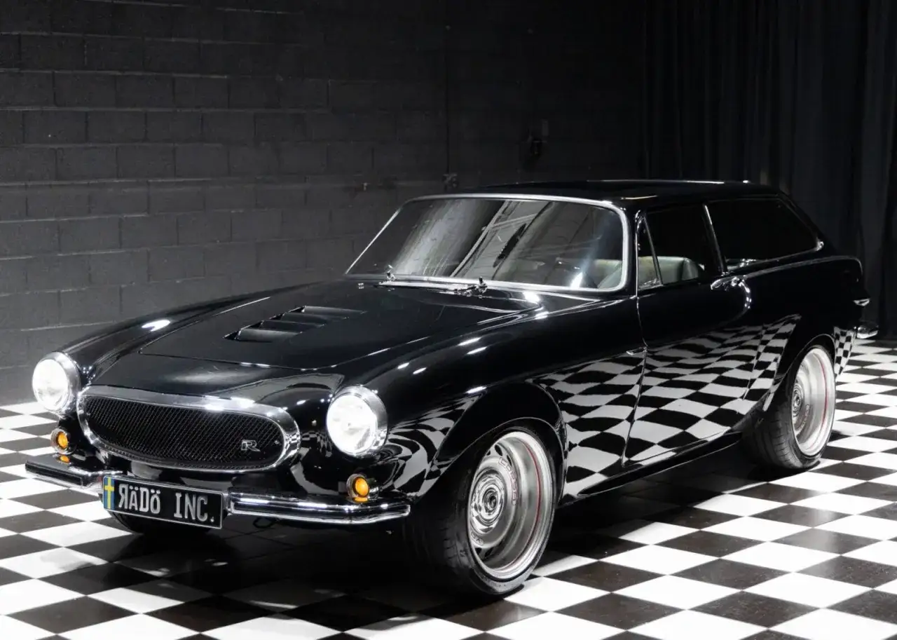Schwarzer Volvo P1800 Shooting Brake mit Chromdetails und auff&auml;lligen Felgen auf kariertem Boden.