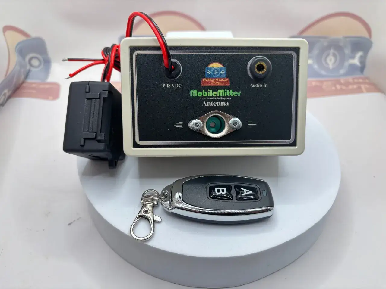 Mit diesem Gerät lässt sich ein altes Autoradio mit dem Handy verbinden. Es hat einen Audio-In-Anschluss und wird mit 6-12 VDC betrieben. Ein Schlüsselanhänger ist ebenfalls abgebildet.