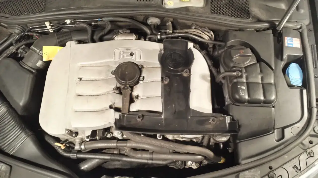 Der Motorraum eines Autos mit einem silbernen w8 Motor, K&uuml;hlmittelbeh&auml;lter und anderen Komponenten.
