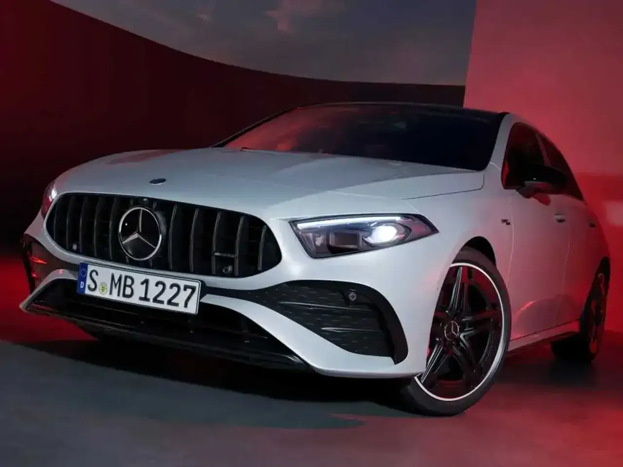 Sportlicher Mercedes A-Klasse mit markantem Kühlergrill und AMG-Felgen, beleuchtet von rotem Licht.