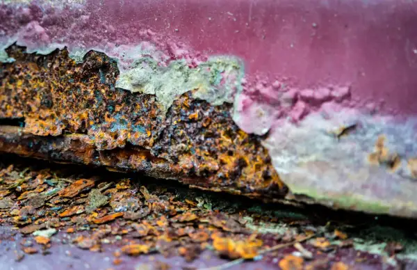 Stark verrostete Kante mit abgeblätterter roter Farbe. Ein Beispiel für entrosten mit Essig und Backpulver.