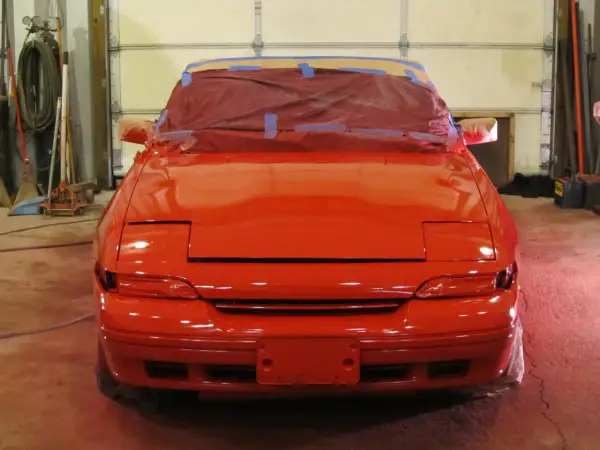 Roter Sportwagen in der Werkstatt, bereit für die Lackierung. Die Frage "was kostet eine Lackierung?" beschäftigt den Besitzer.