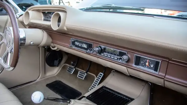 Armaturenbrett eines Oldtimers mit altem Autoradio. Mit einem Adapter lässt sich das alte Autoradio mit dem Handy verbinden, um Musik zu hören.
