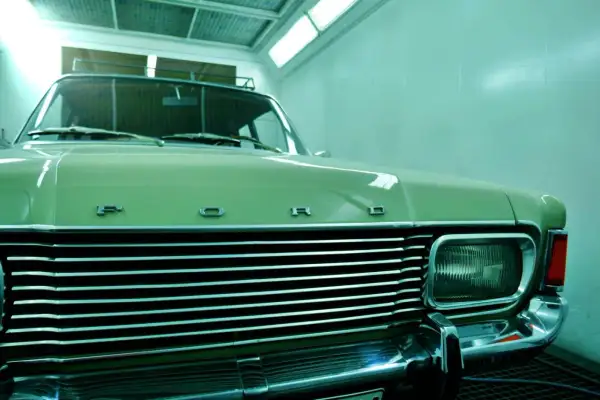 Ein hellgrüner Oldtimer mit Chromgrill und "FORD"-Schriftzug wartet auf das Lackieren. Die Kosten für das Oldtimer lackieren sind hier ein Thema.