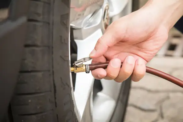Hand befestigt Schlauch an Reifenventil für den Reifendruck am Auto.