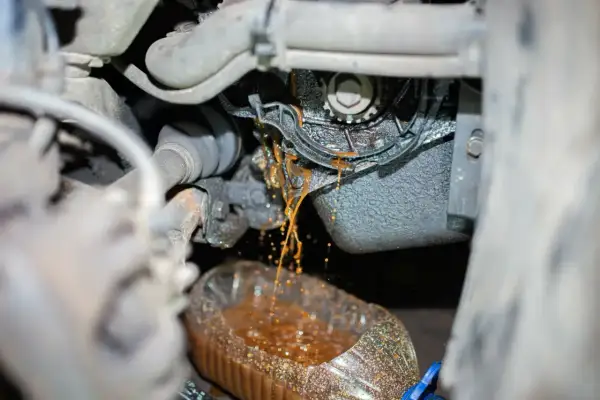 Flüssigkeit tropft aus der defekten Wasserpumpe eines Autos in einen Behälter.