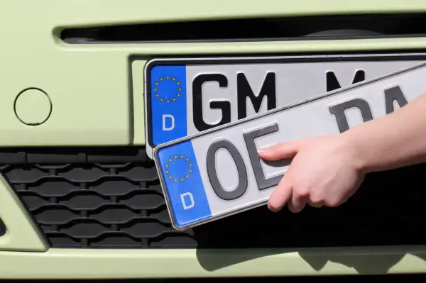 Hand wechselt Kennzeichen. Vorbereitung zum auto ummelden.