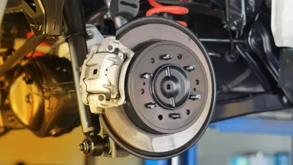 Nahaufnahme einer Autobremsanlage. Ein Mechaniker prüft, wann bremsscheiben wechseln, um die Sicherheit zu gewährleisten.