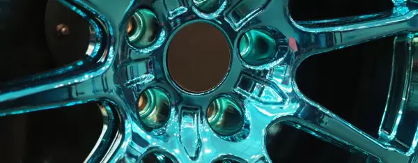 Glänzende Felgen, frisch lackiert in einem auffälligen Türkis. Die Spiegelung des Lichts auf der glatten Oberfläche lässt die Felgen fast lebendig wirken.