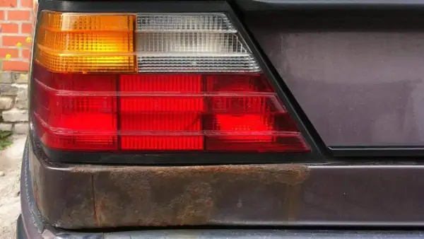 Rost unter Lack am Heckleuchtenbereich eines Autos. Zeit, den Rost unter Lack zu entfernen und das Fahrzeug zu retten.