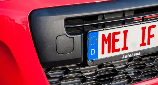 Rotes Kennzeichen "MEI IF" an einem roten Auto, bereit für das Fahrtenbuch.