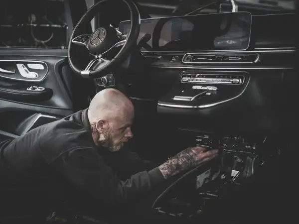 Ein Mechaniker mit Tattoos repariert den Anlasser eines modernen Autos.