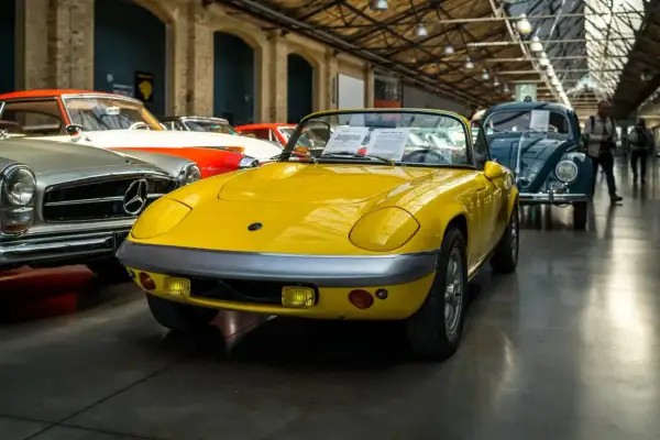 Gelber Lotus Elan Sprint, Baujahr 1972, mit dem Kennzeichen 07. Daneben ein Mercedes-Benz und ein VW Käfer.
