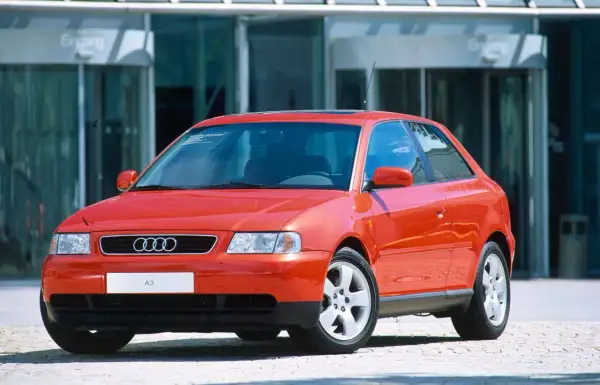 Roter Audi A3 vor einem modernen Gebäude. Ein Klassiker, der bald das Youngtimer Kennzeichen tragen darf.