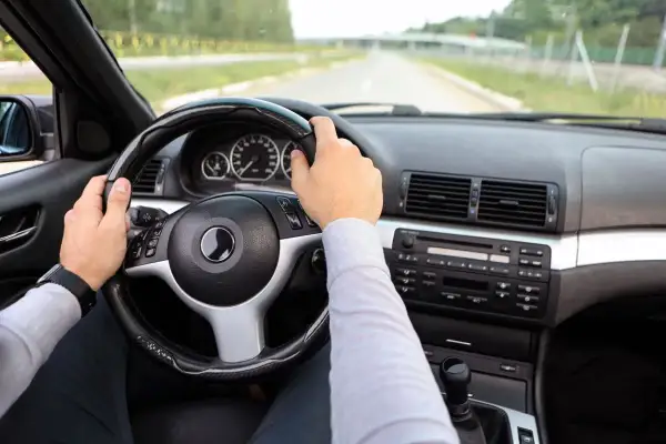 Fahrer hält das Lenkrad, das leicht schief steht. Ein Hinweis, dass das Lenkrad schief selber einstellen nötig sein könnte.
