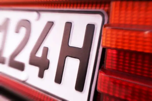 Nahaufnahme eines Nummernschilds mit der Aufschrift "124H". Die rote Rückleuchte des Autos ist daneben zu sehen. Hoffentlich gibt es keine 07-Kennzeichen-Strafe.