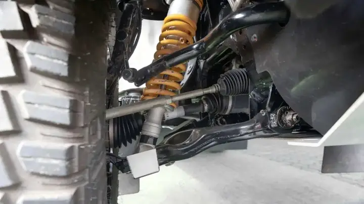 Detailaufnahme der Radaufhängung eines Fahrzeugs. Ein defekter Querlenker kann sich durch Geräusche und schlechtes Fahrverhalten bemerkbar machen.