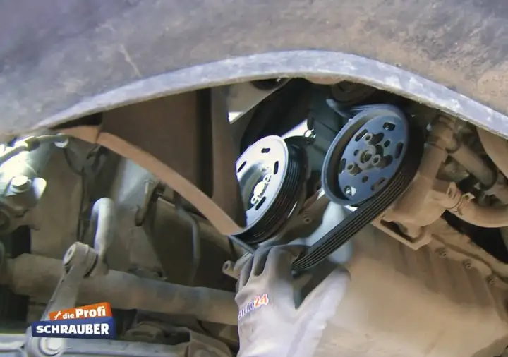 Ein Mechaniker wechselt einen Keilriemen. Die Keilriemen wechseln Kosten sind oft überschaubar.